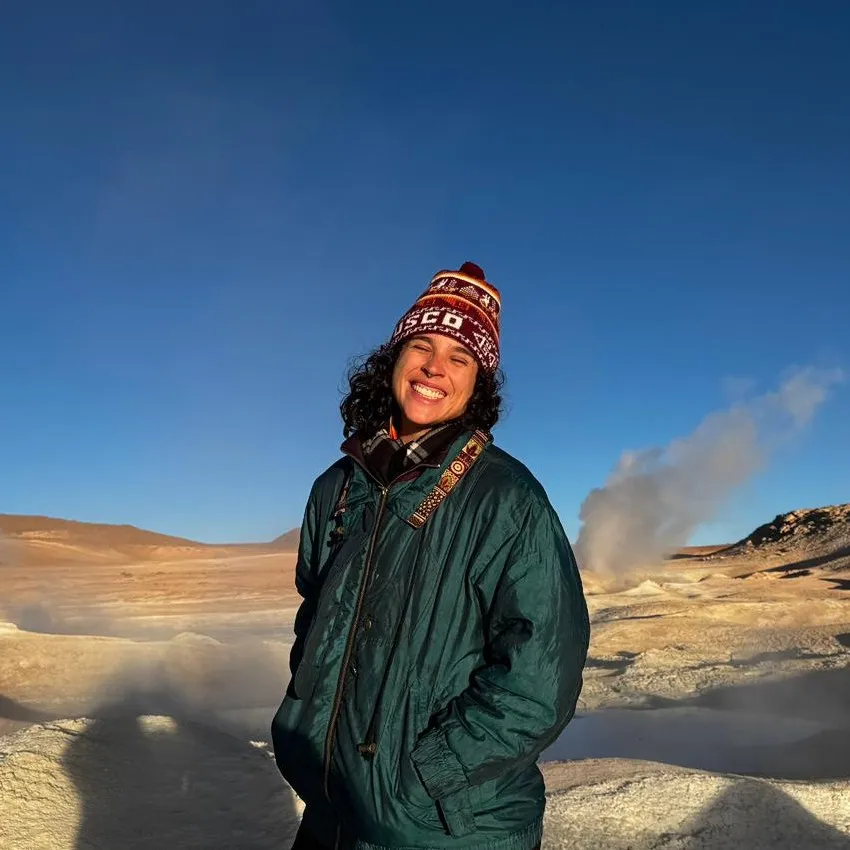 Tatiana Burgos sorrindo em uma paisagem de gêiseres no altiplano